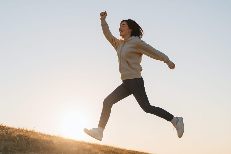 次のステップに進む日本人女性がジャンプしている写真(Japanese woman jumping to the next step)