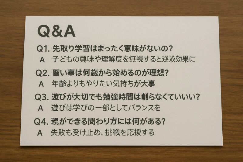 木目のテーブルの上に置かれたQ&Aカードに、子どもの教育に関する4つのよくある質問とその答えが日本語で印刷されている(A white Q&A card placed on a wooden table, printed with four frequently asked questions and answers in Japanese about children's education)
